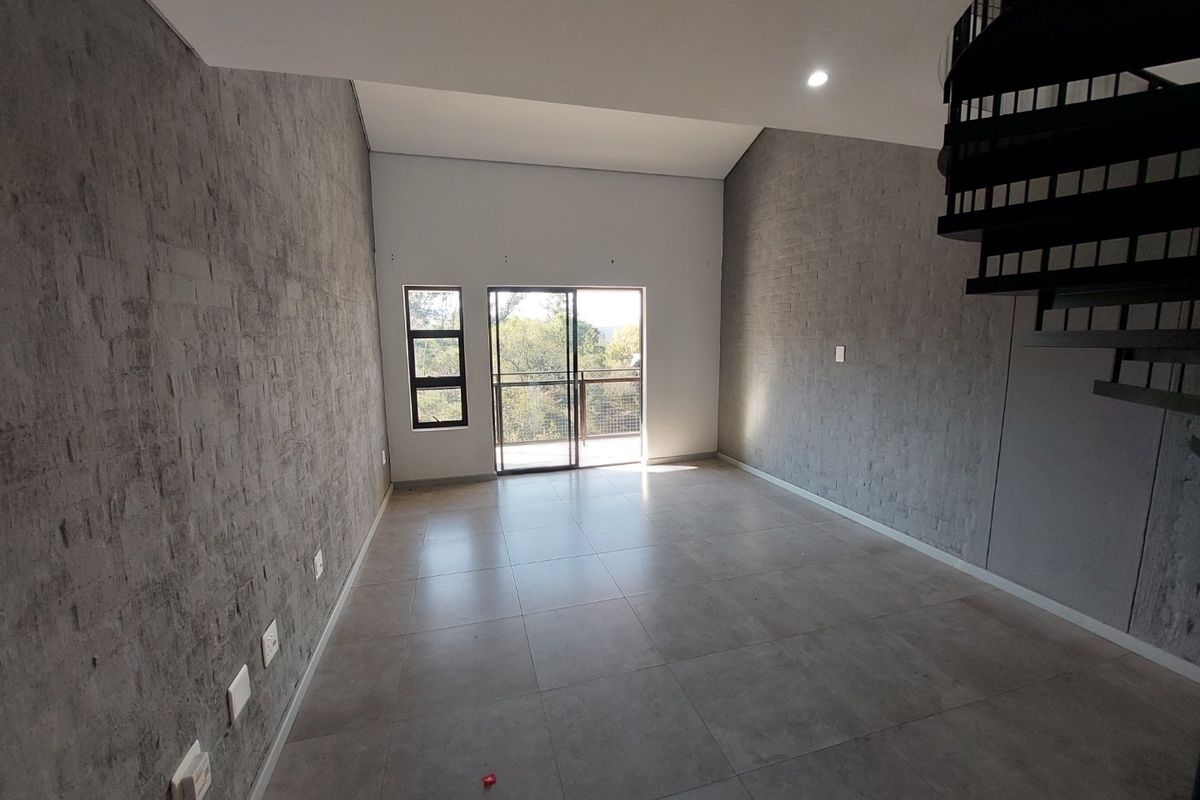 Spacious open-plan living area featuring modern grey tiled floors, textured feature walls, a striking spiral staircase, and access to a private balcony.