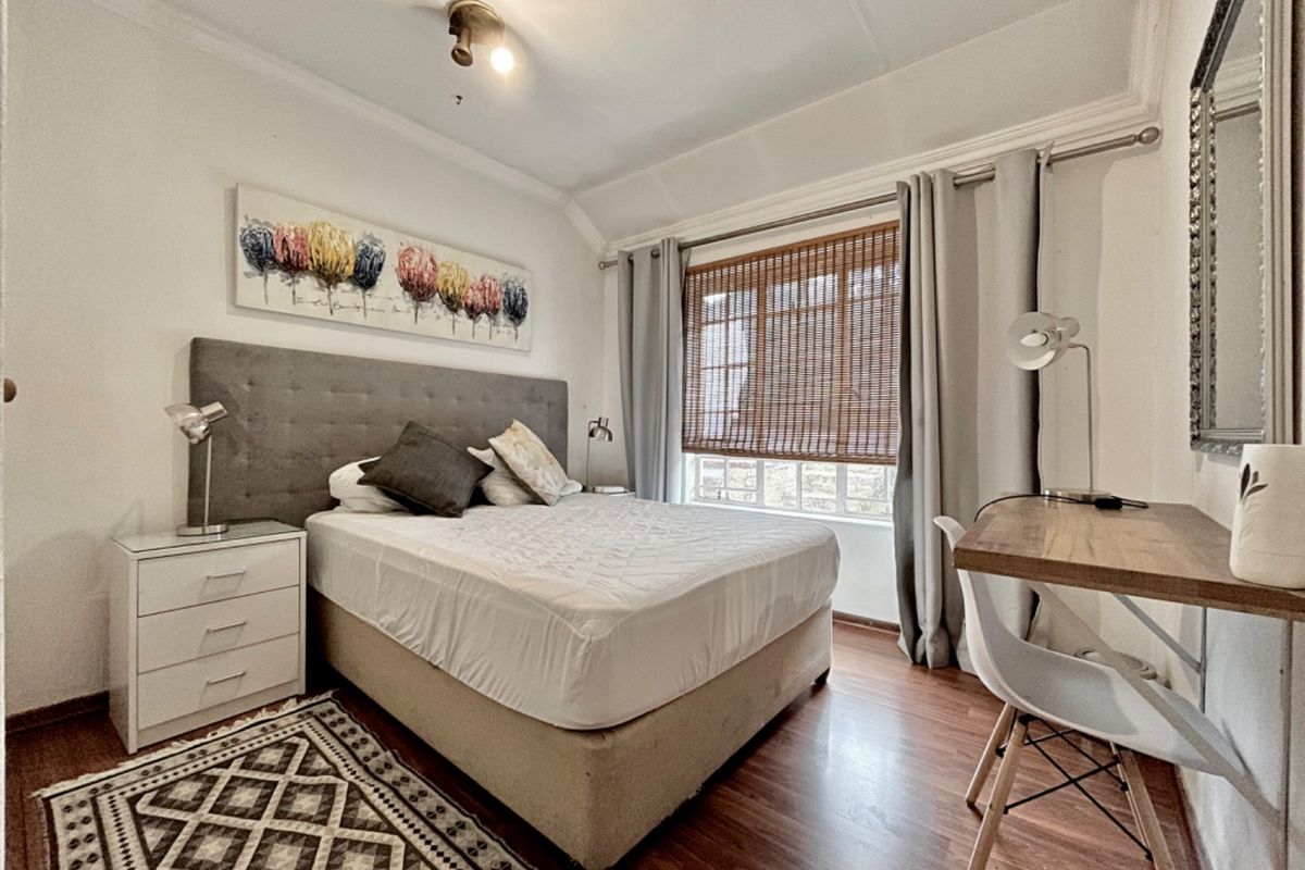 A well-maintained bedroom featuring laminate flooring, coved ceilings, and window blinds, offering a comfortable and functional living space.