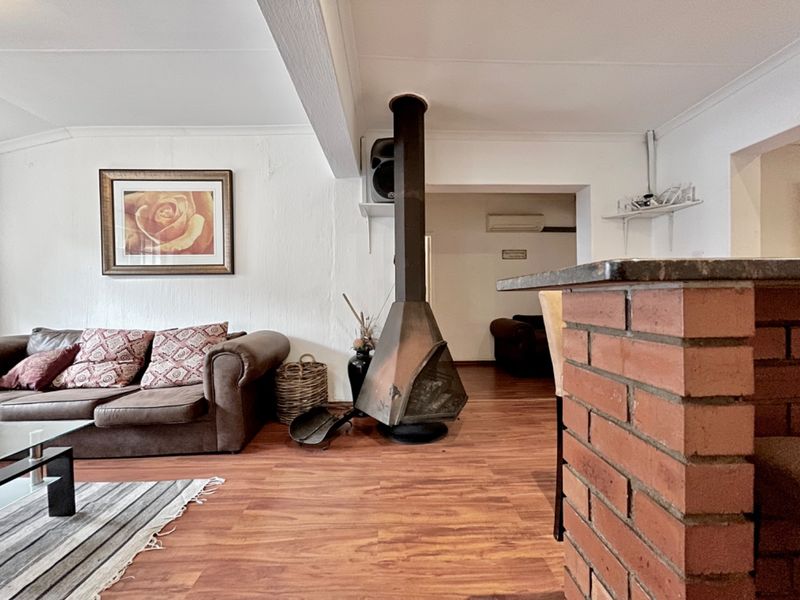 Living room featuring a central freestanding fireplace, brick breakfast bar, and laminate flooring, with an adjacent area showing an air conditioning unit.