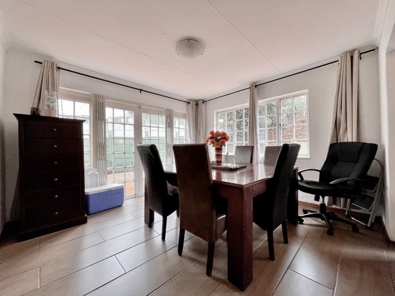 A bright dining room featuring tiled flooring, large windows, and french doors providing natural light and access to the exterior.