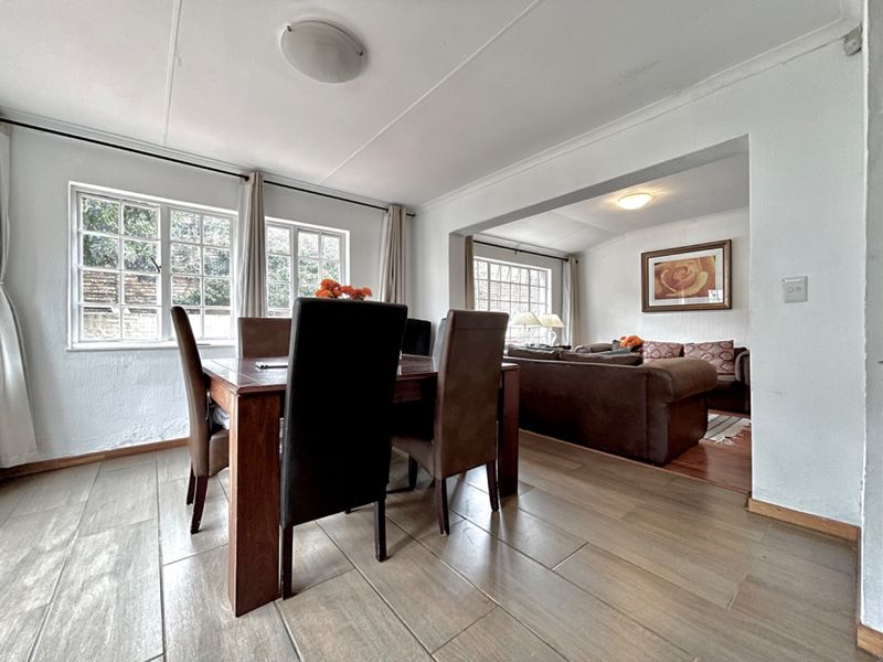 Open-plan living and dining area featuring tiled flooring, neutral walls, and large multi-pane windows providing natural light.