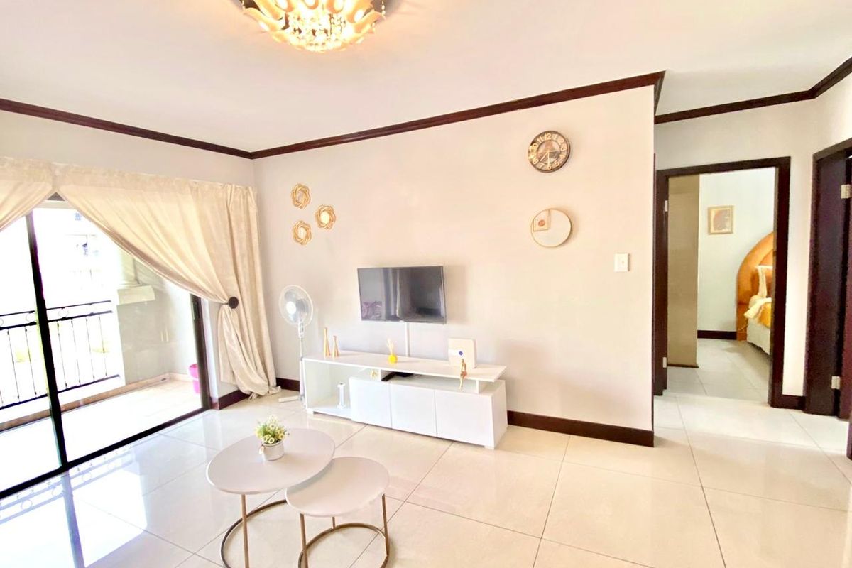 Bright living room featuring large format floor tiles, crown molding, and a sliding glass door providing access to an attached balcony.