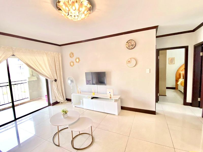 Bright living room featuring large format floor tiles, crown molding, and a sliding glass door providing access to an attached balcony.