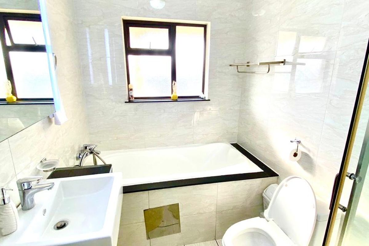 A modern bathroom featuring a built-in bathtub, wall-mounted basin, toilet, and a separate shower enclosure with neutral tiled finishes.