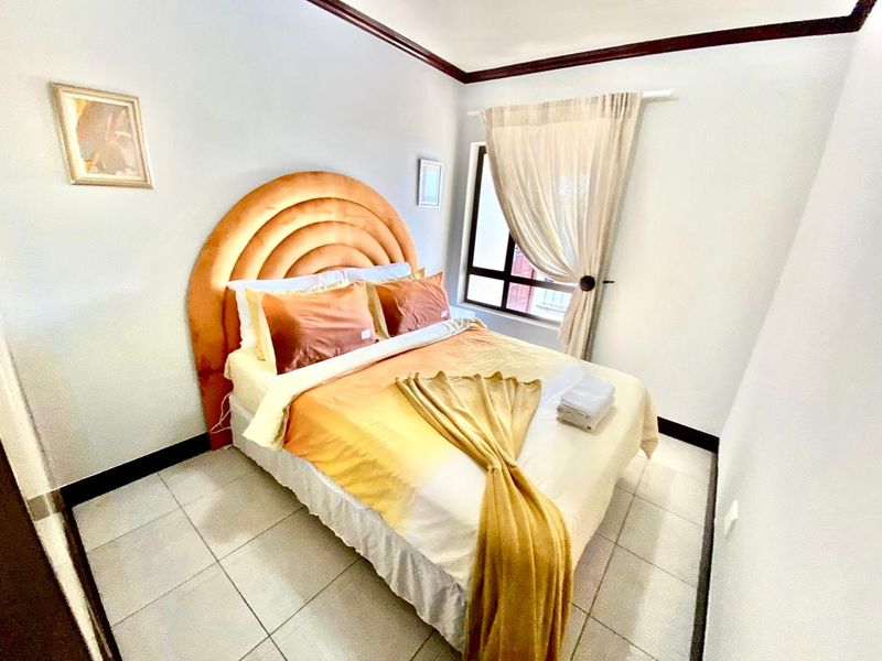 A compact bedroom featuring tiled flooring, crown molding, and a window with curtains.