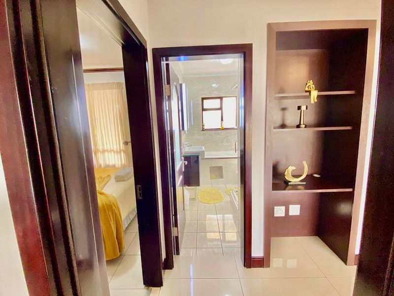 A hallway featuring tiled flooring and built-in shelving, providing access to a bedroom and a bathroom.