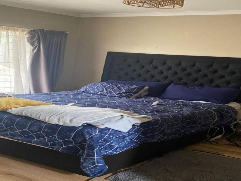A bedroom featuring laminate flooring and neutral wall finishes, providing a comfortable and functional sleeping space.