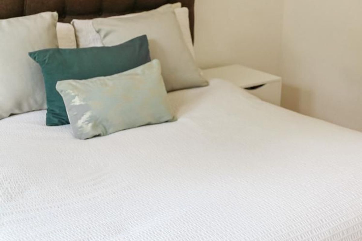 A close-up view of a bedroom space featuring a tufted headboard and neutral wall finishes.