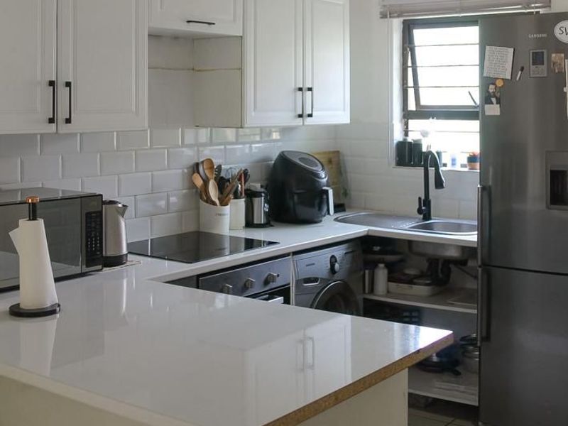 A functional kitchen featuring white cabinetry, subway tile backsplash, quartz countertops, and integrated appliances, with an open-plan layout and tiled flooring.