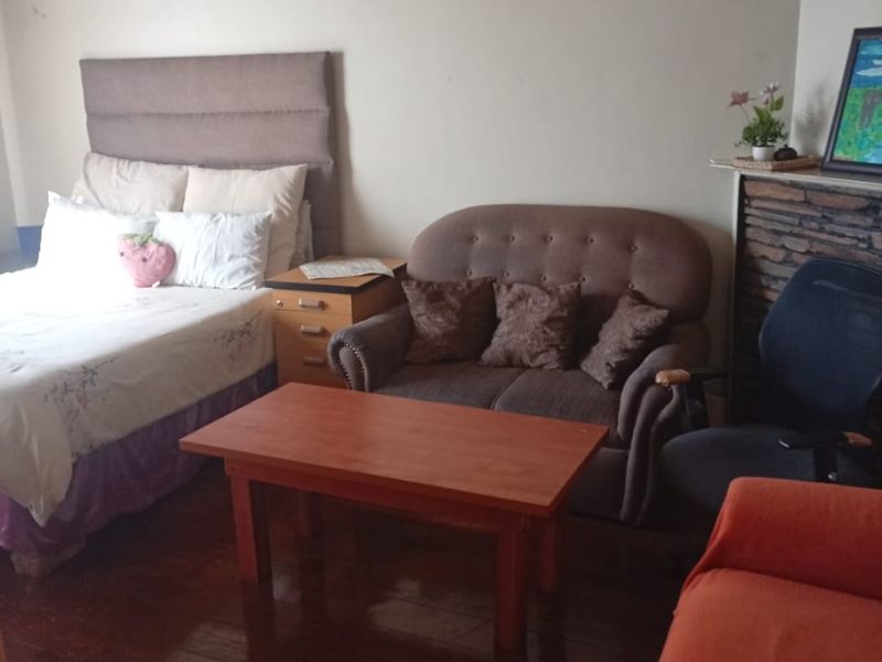A bedroom featuring hardwood flooring and a stone fireplace surround, currently showing signs of ceiling wear and water damage.