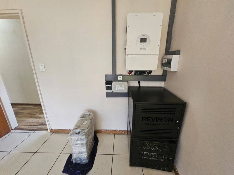 Utility area featuring a wall-mounted solar inverter and a floor-standing lithium battery storage system for off-grid power backup.