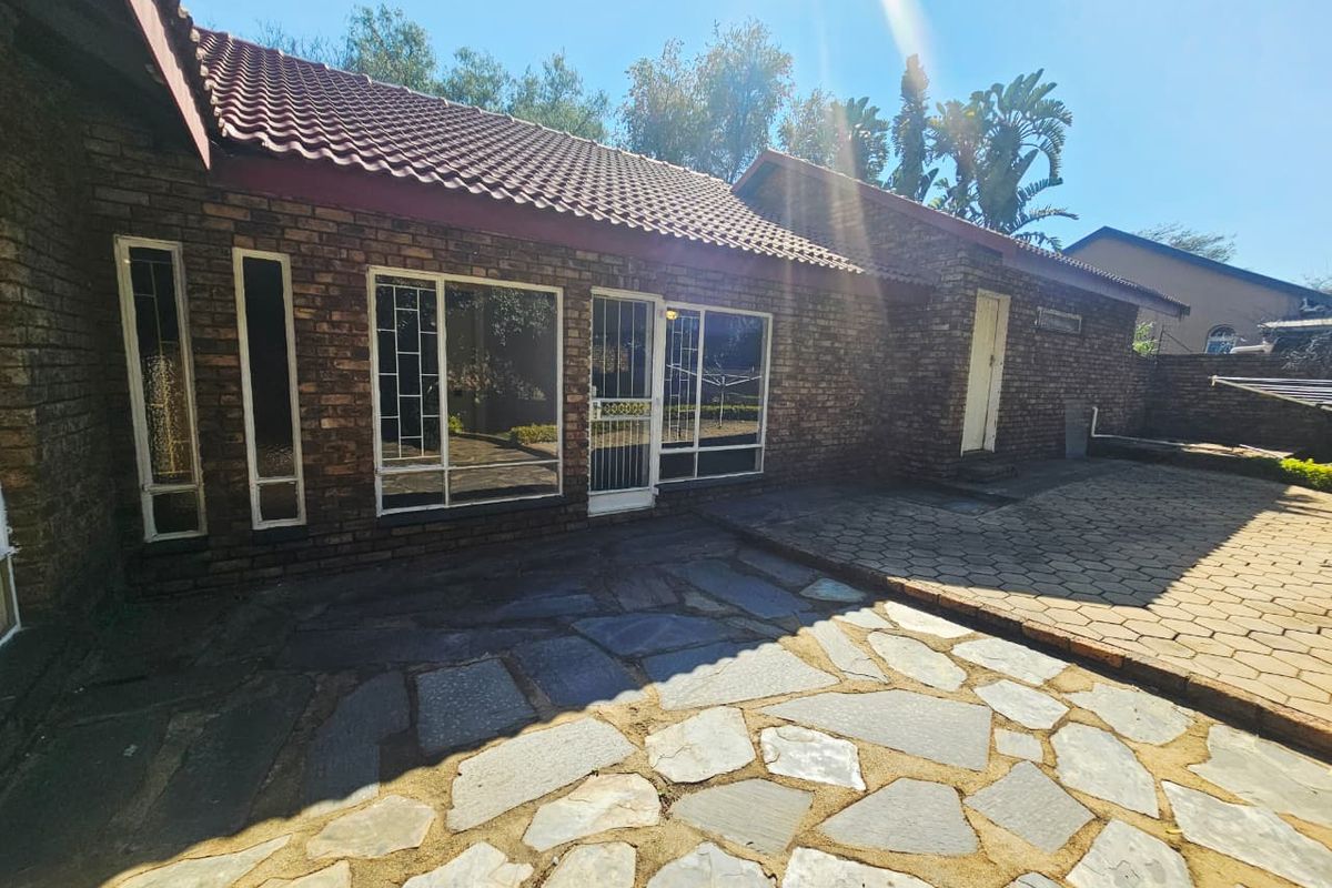 Rear exterior view of a face brick house featuring a paved patio area and secure access points.