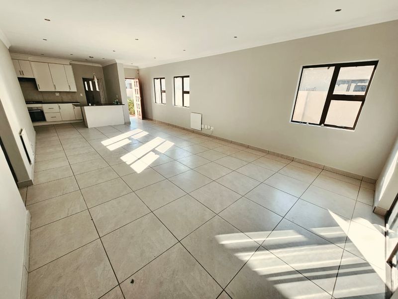 Spacious open-plan living area featuring tiled floors, recessed lighting, and a modern kitchen with built-in cabinetry, oven, and hob.