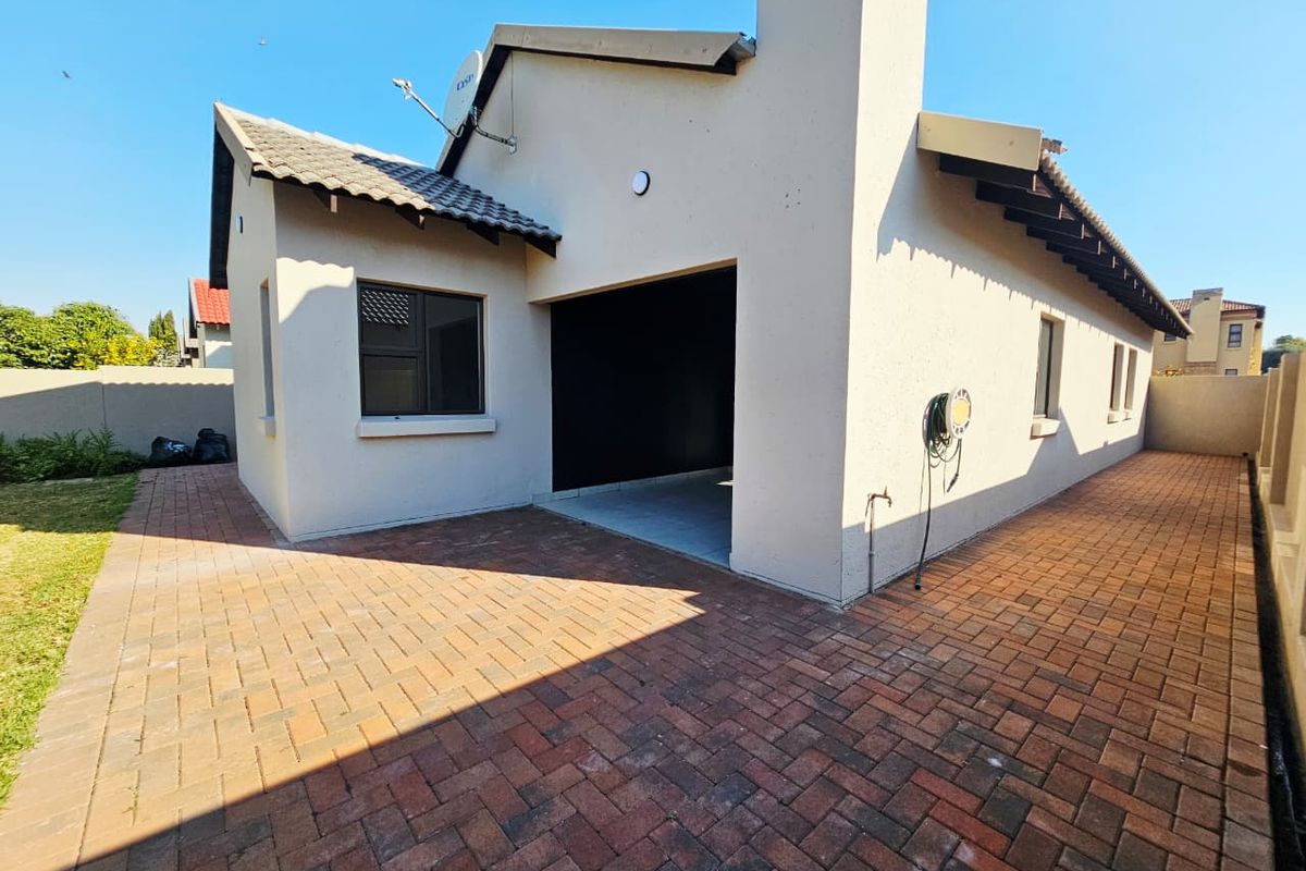 Rear view of the property featuring a paved courtyard, tiled roof, and exterior chimney structure.