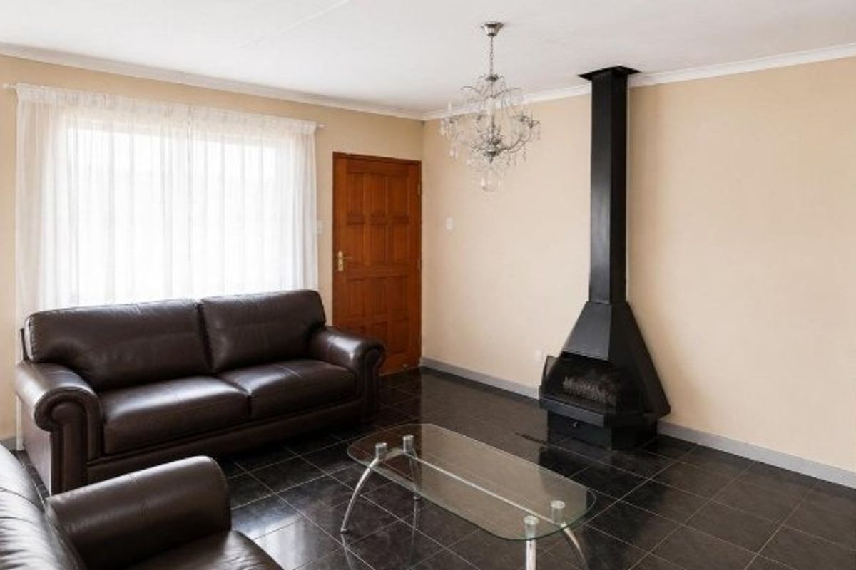 A living room featuring dark tiled flooring, a prominent black freestanding fireplace, and a decorative chandelier, providing a functional and cozy living space.