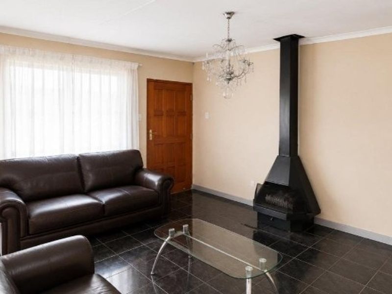 A living room featuring dark tiled flooring, a prominent black freestanding fireplace, and a decorative chandelier, providing a functional and cozy living space.