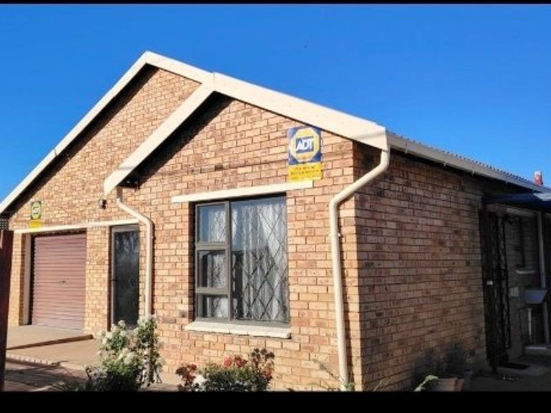 Front elevation of a face brick house featuring a garage, security gates, and security bars on the windows.