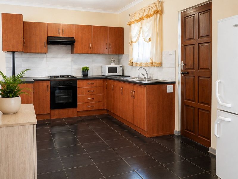 Functional kitchen featuring wood-finish cabinetry, built-in oven with gas hob, dark tiled flooring, and direct access to an exterior door.