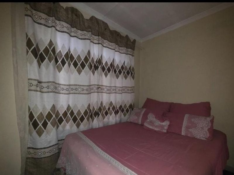 A standard bedroom featuring neutral wall finishes and a window with patterned curtains.