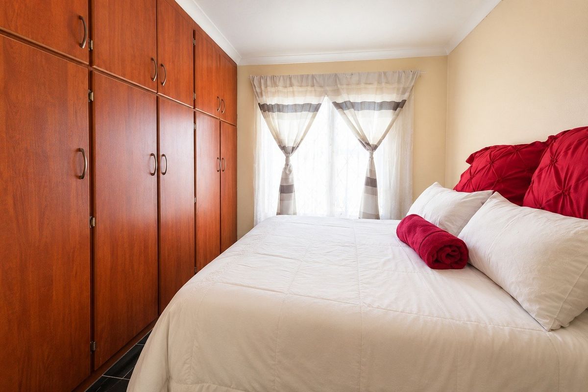 A bedroom featuring extensive floor-to-ceiling built-in wooden cupboards and natural light from the window.