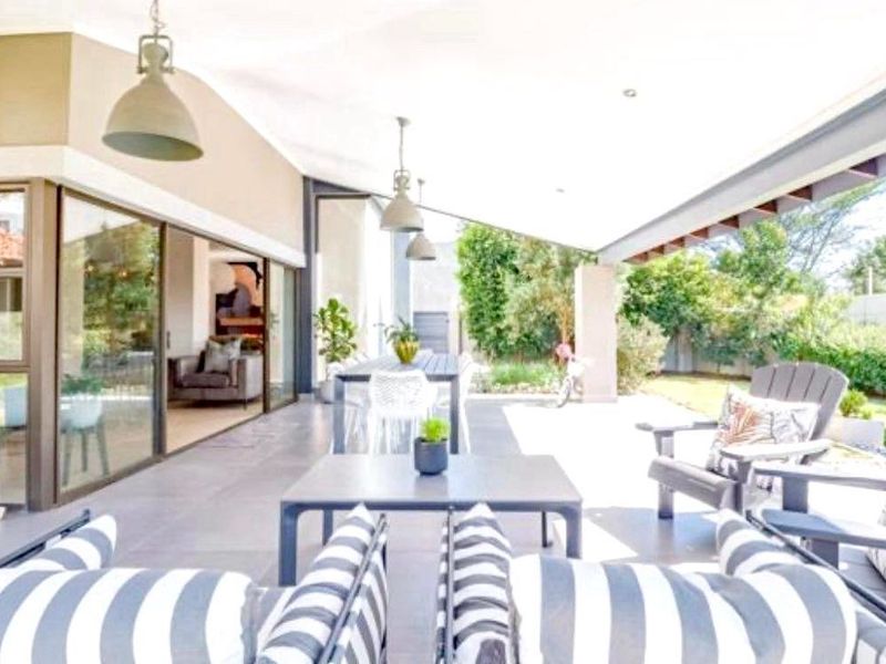 Spacious covered patio featuring large sliding glass doors, tiled flooring, and recessed lighting, providing a seamless transition to the outdoor garden area.