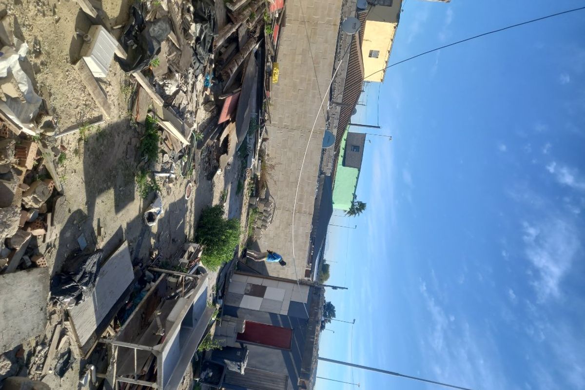 A vacant residential plot featuring a boundary wall and debris, requiring significant site clearance and preparation for future development.