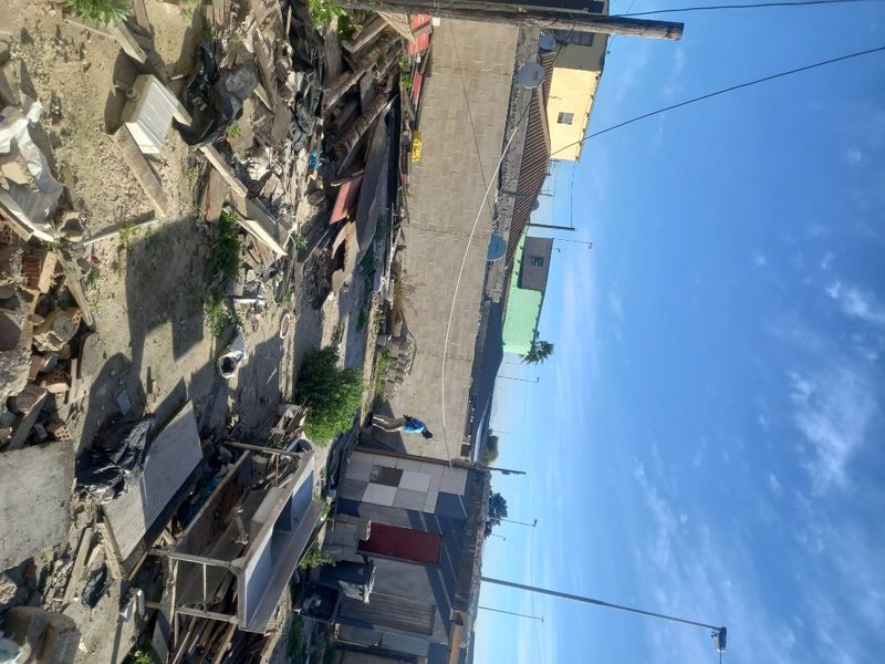 A vacant residential plot featuring a boundary wall and debris, requiring significant site clearance and preparation for future development.