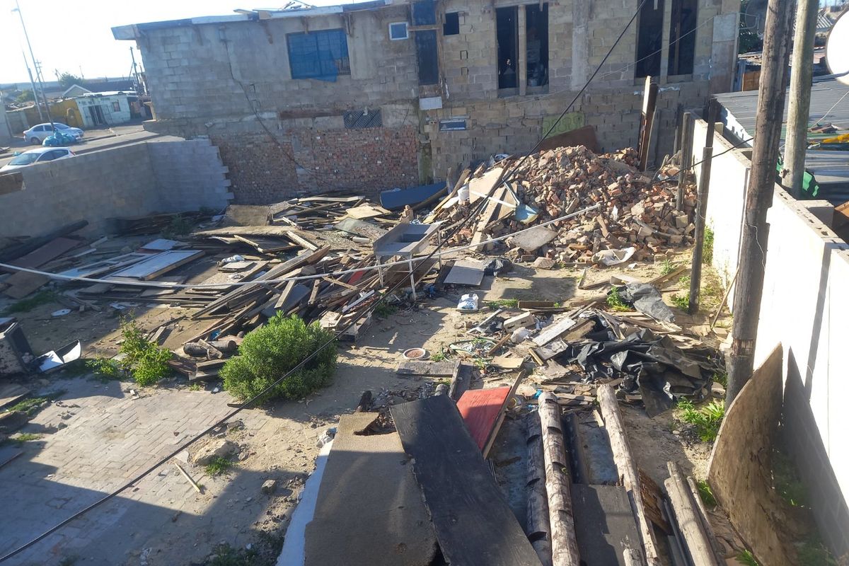 A vacant residential plot featuring significant demolition debris and unfinished structural elements, requiring extensive site clearance and development.