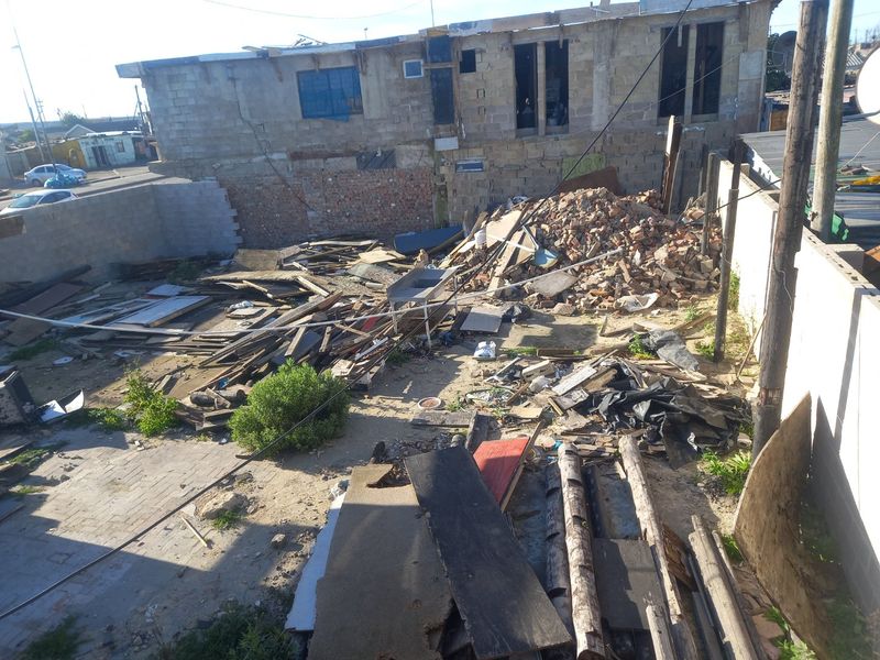 A vacant residential plot featuring significant demolition debris and unfinished structural elements, requiring extensive site clearance and development.