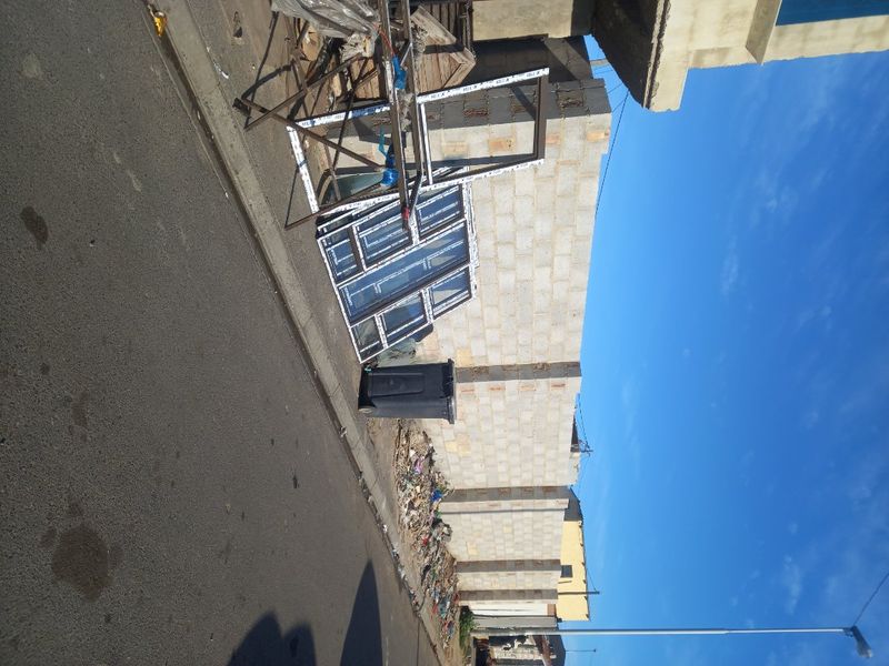 A view of a residential property under construction, featuring a concrete block boundary wall and adjacent street frontage.