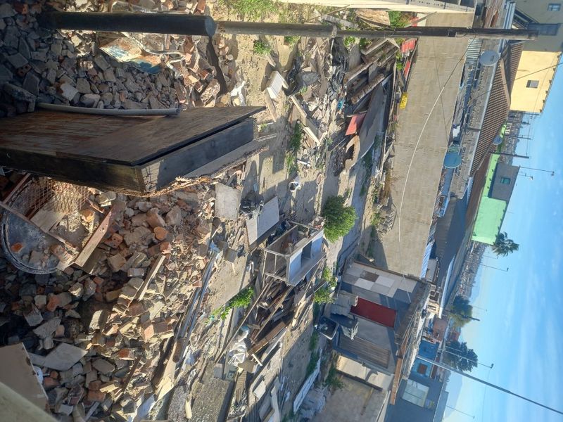 An elevated view of a vacant residential plot covered in significant construction debris and site waste, requiring extensive clearing.