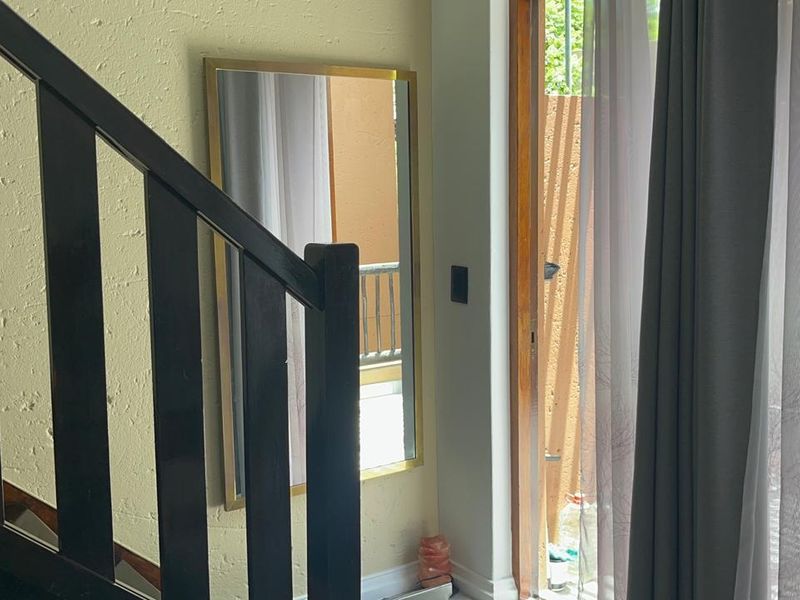 Interior view of a living area featuring a staircase with dark railings and a door providing access to an outdoor balcony space.
