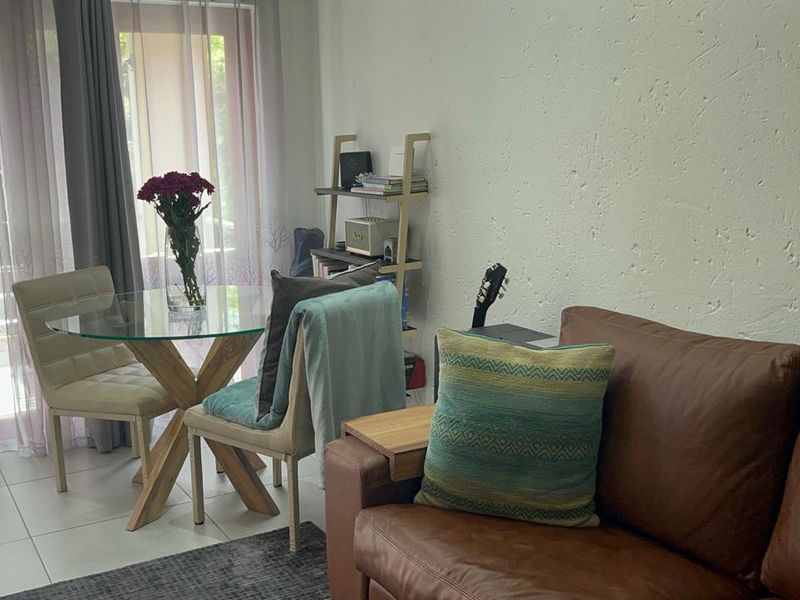 A living room area featuring tiled flooring, textured walls, and a sliding glass door providing access to an outdoor space.