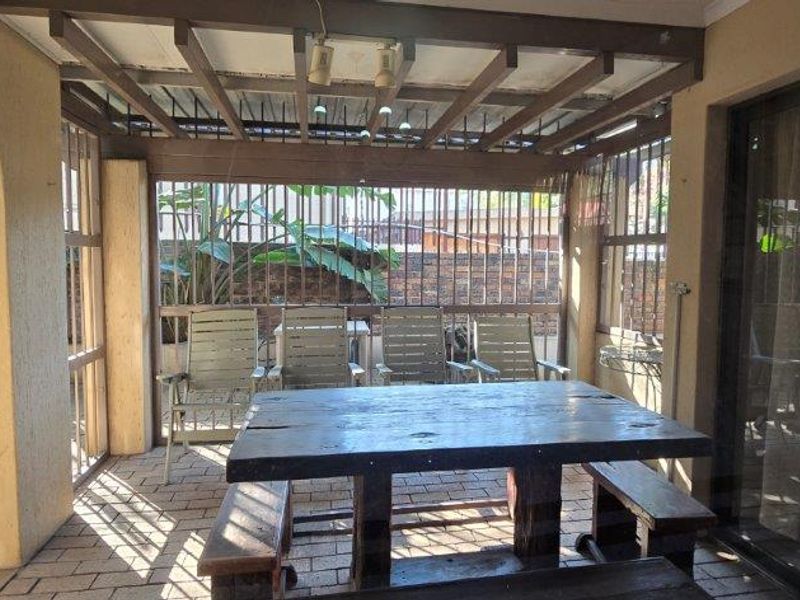 Covered patio area featuring a timber pergola, paved flooring, and secure metal bars, providing a functional outdoor entertainment space.