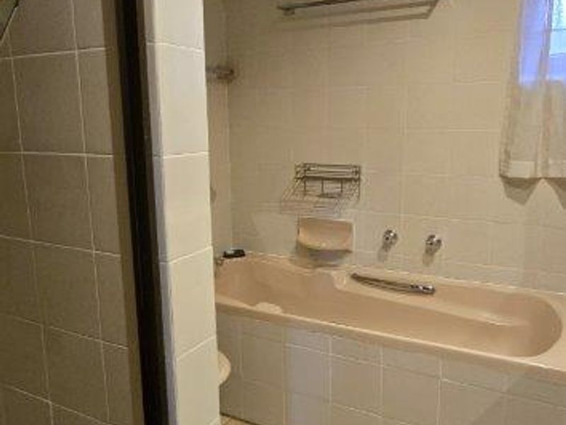 A dated bathroom featuring a built-in bathtub, separate shower enclosure, and neutral wall and floor tiling.