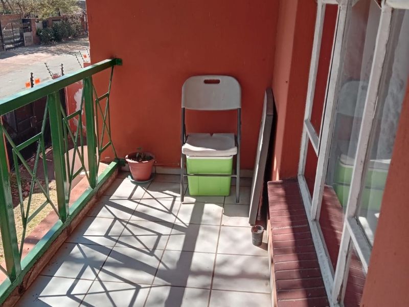 A compact balcony featuring tiled flooring, a metal safety railing, and access to the interior through a large glass sliding door.