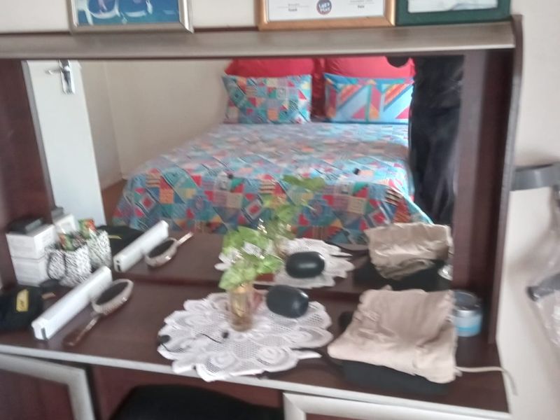 A bedroom featuring a built-in vanity unit with a mirror and a double bed.