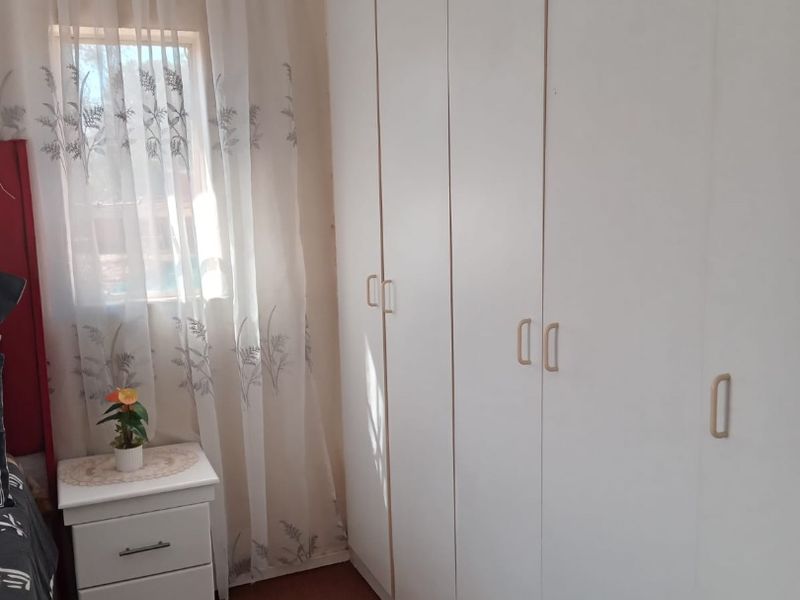 A bedroom featuring floor-to-ceiling built-in cupboards providing ample storage space.