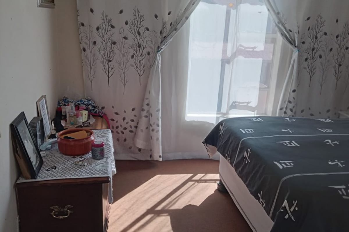 A bedroom featuring carpeted flooring and natural light, currently requiring cosmetic updates to improve the overall finish and appeal.