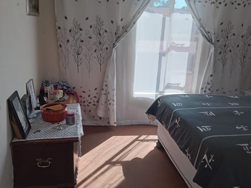 A bedroom featuring carpeted flooring and natural light, currently requiring cosmetic updates to improve the overall finish and appeal.