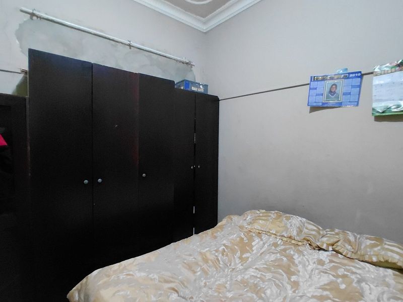 A bedroom featuring a built-in wardrobe and decorative ceiling cornice, currently requiring cosmetic attention to the wall finishes.