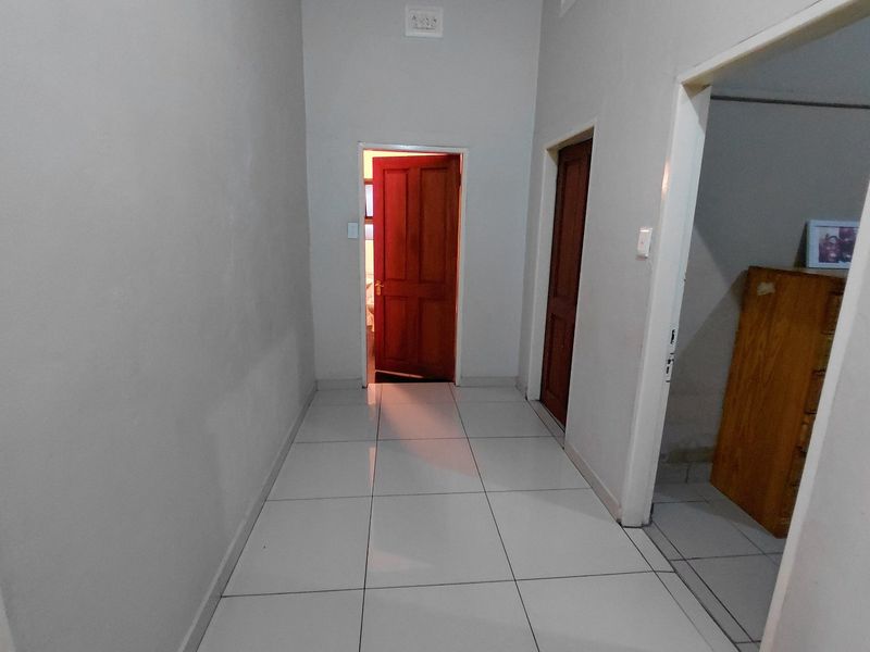 A functional hallway featuring tiled flooring and timber doors, providing access to adjacent rooms within the home.
