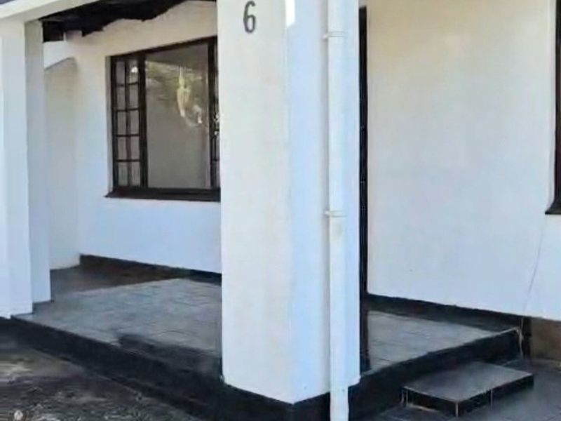 Front entrance of the apartment featuring a covered tiled porch, timber-framed gable detail, and exterior lighting.