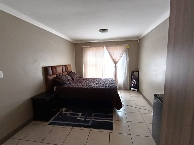 A functional bedroom featuring tiled flooring and neutral wall finishes, providing a clean and simple space ready for personalization.