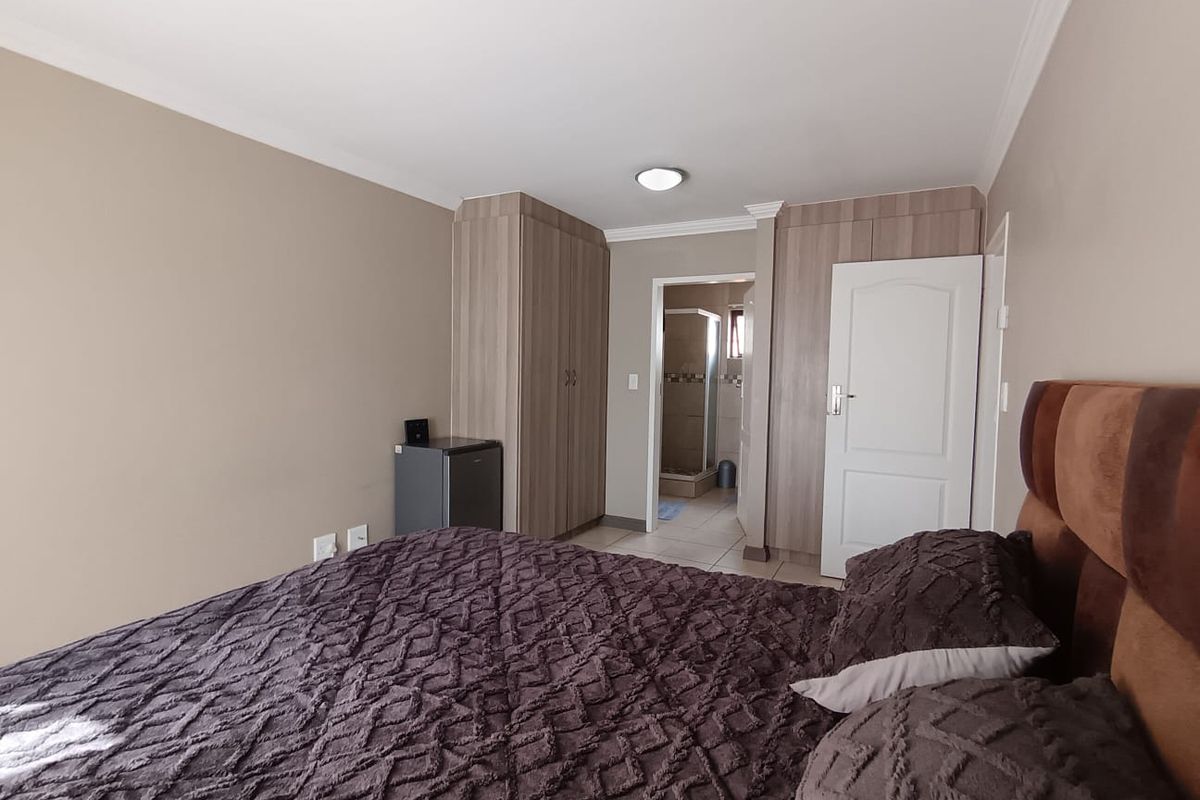A well-maintained bedroom featuring built-in cupboards, neutral wall tones, and direct access to an en-suite bathroom.