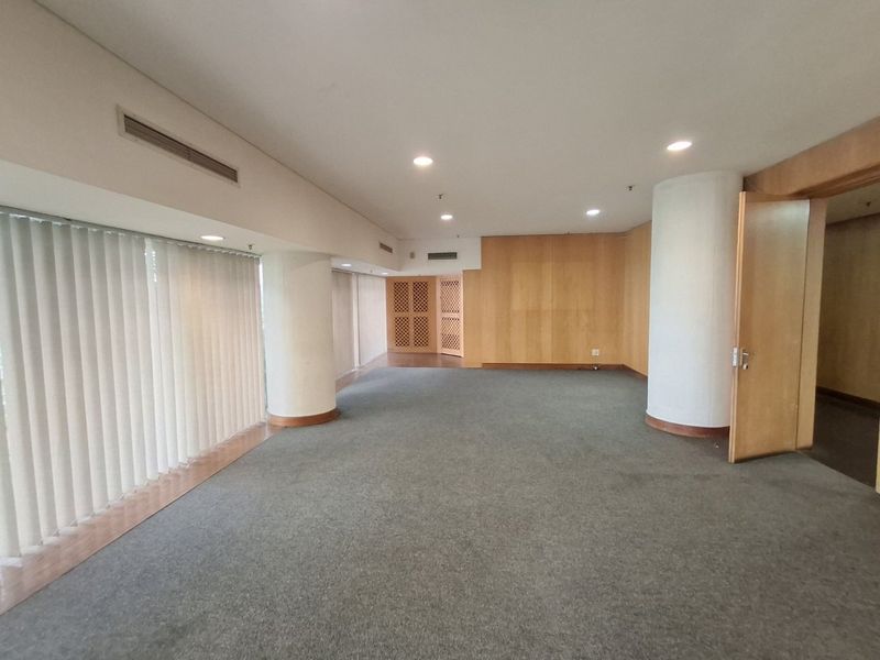 Spacious, empty commercial office area featuring timber veneer wall paneling, recessed lighting, ducted air conditioning, and large windows with vertical blinds.