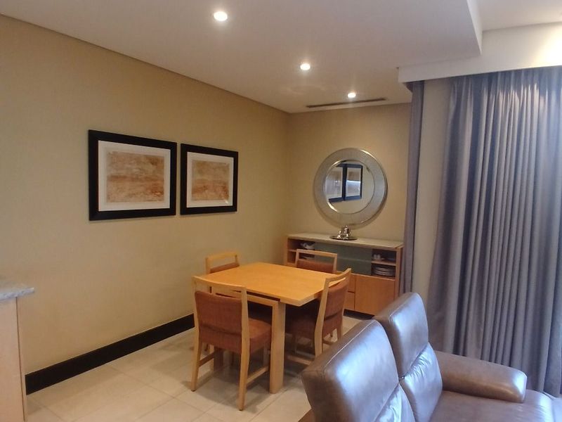 An open-plan living and dining area featuring neutral wall tones, tiled flooring, and recessed ceiling lighting, creating a functional and cohesive living space.