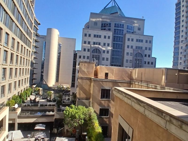 An elevated view overlooking a complex courtyard featuring a swimming pool, landscaped garden areas, and surrounding high-rise apartment buildings.