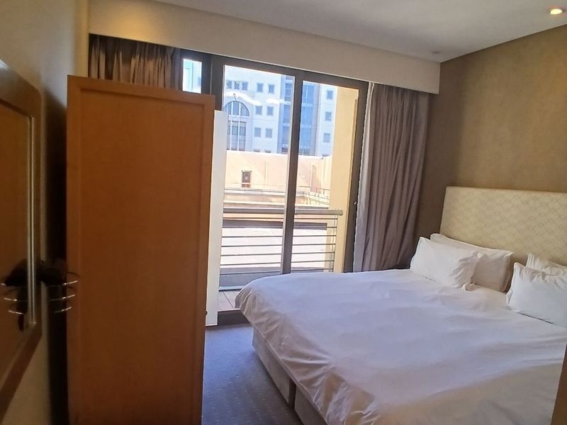 A bedroom featuring carpeted flooring, recessed lighting, and a sliding glass door providing access to a balcony.