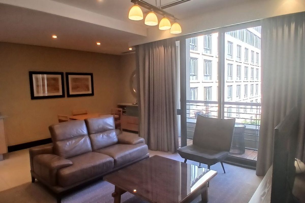 A well-maintained living room featuring recessed lighting, central air conditioning, and large sliding glass doors leading to a private balcony.